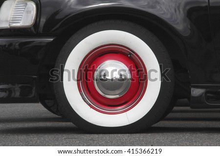 Close up of a Whitewall tyre with red trim and a silver, reflective hubcap/Whitewall Tires/Close on Whitewall tires with red trim. 