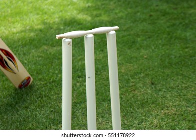 Close Up Of Wickets And Bat Against Grass Background During A Game Of Cricket