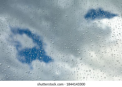 Close up of a window with rain drops falling down. Focus on rain drops. Rain drops on rainy day on outside window glass with blurred edges. Rain outside window pane in spring day.