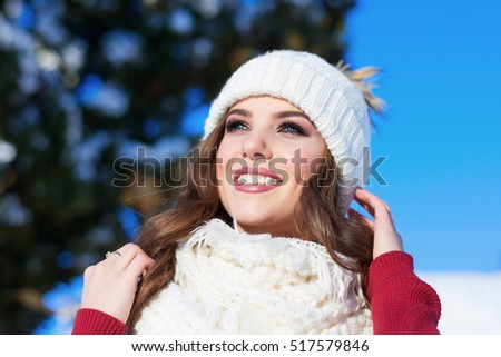 close up Winter portrait of a young smiling woman in a pink hat and gloves