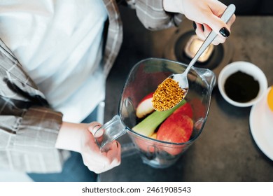 Close up woman adding bee pollen during making smoothie on the kitchen. Superfood supplement. Healthy detox vegan diet. Healthy dieting eating, weight loss program. Selective focus