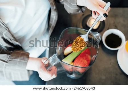 Close up woman adding bee pollen during making smoothie on the kitchen. Superfood supplement. Healthy detox vegan diet. Healthy dieting eating, weight loss program. Selective focus