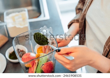 Close up woman adding spirulina or chlorella powder during making smoothie on the kitchen. Superfood supplement. Healthy detox vegan diet. Healthy dieting eating, weight loss program. Selective focus