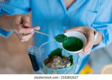 Close Up Woman Adding Spirulina Green Powder During Making Smoothie On The Kitchen. Superfood Supplement. Healthy Detox Vegan Diet. Healthy Dieting Eating, Weight Loss Program. Selective Focus.