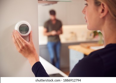 Close Up Of Woman Adjusting Wall Mounted Digital Central Heating Thermostat Control At Home