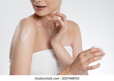 Close up of woman applying body lotion on bare shoulders