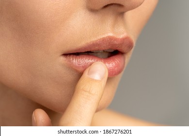 Close up of woman applying moisturizing nourishing balm to her lips with her finger to prevent dryness and chapping in the cold season. Lip protection.  - Shutterstock ID 1867276201