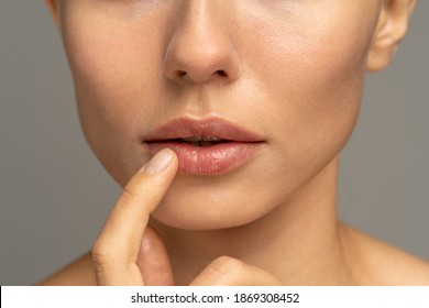 Close up of woman applying moisturizing nourishing balm or ointment to her lips with her finger to prevent dryness and chapping in the cold season. Lip protection.  - Shutterstock ID 1869308452