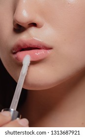 Close Up Of Woman Applying Transparent Lip Gloss With Applicator. Cropped Shot Of Girl Doing Makeup On Her Lips.