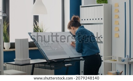 Close up of woman architect taking notes on blueprints plans to design building layout. Engineer planning urban construction project and structure to work on architectural development. [[stock_photo]] © 