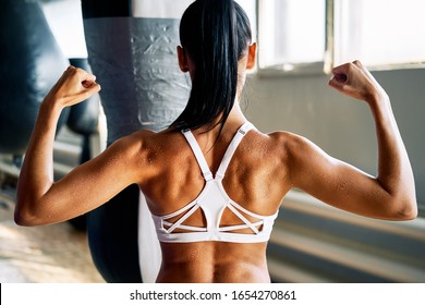 Close up of woman back with flexing her muscles in sweat on skin after workout. Female bodybuilder with perfect biceps                          