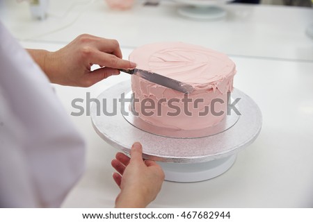 Close Up Of Woman In Bakery Decorating Cake With Icing