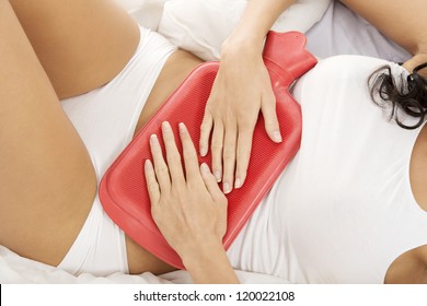 Close Up Of Woman Belly With Hot Water Bottle In Bed