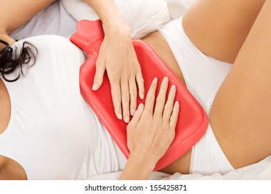 Close Up Of Woman Belly With Hot Water Bottle In Bed