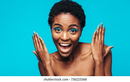 Close Up Of Woman With Blue Eye Shadow And Nail Paint Against Blue Background. Excited Female Model Showing Her Vivid Makeup.