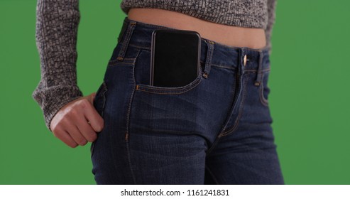 Close up of woman in blue jeans with phone in front pocket on greenscreen