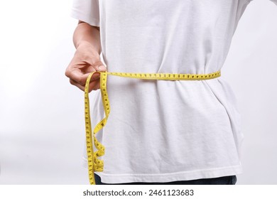 Close up woman in blue shirt measuring her waist with yellow measuring tape. Weight loss, slim body, healthy lifestyle concept. Figure control and counting calories. Successful diet plan. - Powered by Shutterstock