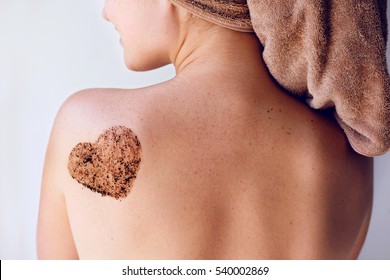 Close up woman body care with coffee scrub on her back and shoulder in the bathroom with towel on head. Beauty treatment and skin care therapy.