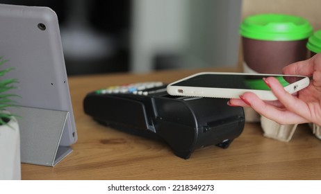 Close Up Woman Is Buying Coffe In Coffee-shop And Paying With Smartphone Making Contactless Payment. Modern Technology And Banking Concept.