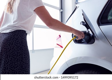Close Up Of Woman Charging Electric Vehicle With Cable In Garage At Home - Shutterstock ID 1499395172