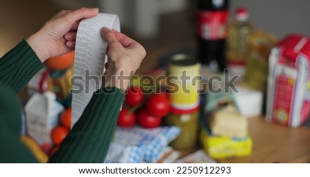 Close up woman checks paper check after shopping for groceries. Cooking and eating product on background.