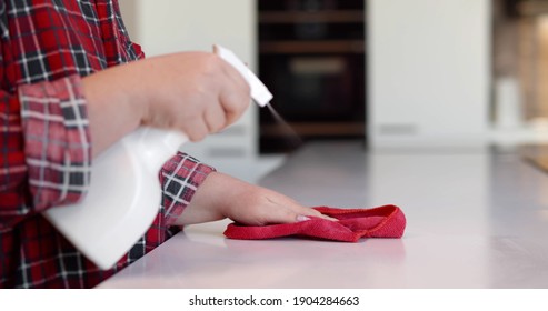 Close Up Of Woman Cleaning Kitchen Counter With Cloth And Spray At Home. Cropped Shot Of Housewife Using Detergent Sprayer And Rag Wiping Table In Kitchen