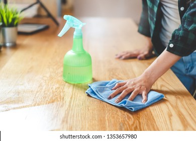 Close up woman cleaning kitchen using cleanser spray and cloth.
