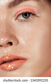 close up of woman with coral glitter makeup looking at camera