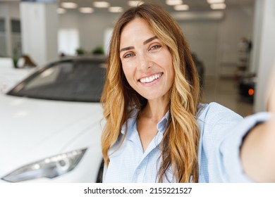 Close Up Woman Customer Buyer Client In Blue Shirt Do Selfie Shot Pov Mobile Phone Choose Auto Want To Buy New Automobile In Car Showroom Vehicle Salon Dealership Store Motor Show Indoor Sales Concept