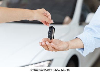 Close up woman customer buyer client female hand arm take car key from salesman chooses auto buy new white modern automobile in showroom vehicle salon dealership store motor show indoor Sales concept