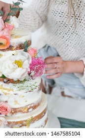 Close Up Of Woman Decorating Naked Wedding Cake With Flowers, Baker With Modern Style Tiered Cake, White Background