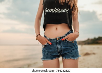 Close up of woman in denim shorts, front view. Young beautiful woman on the background of the sea. Girl model.