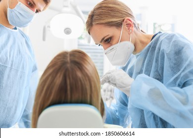 Close Up Of Woman Dentist With Face Mask And With The Help Of An Assistant And Medical Equipment Works With Female Patient In Dental Office