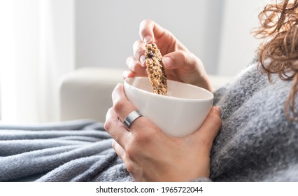 Close up of a woman dipping a healthy cookie into her mug during breakfast - Powered by Shutterstock