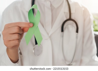 Close Up Of Woman Doctor In White Coat With Stethoscope Holding Lime Green Ribbon Sitting On Couch, Mental Health Awareness, World Mental Health Day, World Kidney Day, Organ Donation Concept