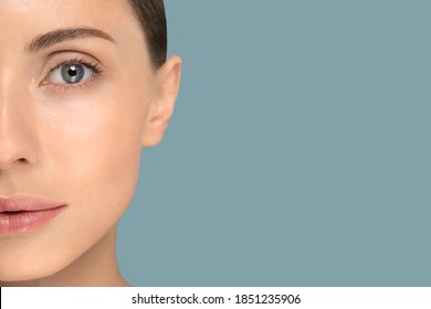 Close Up Of Woman Face With Perfect Fresh Clean Skin Without Make Up And Wrinkles, Looking At Camera Over Studio Blue Background. Youth, Beauty Product, Eyesight Advertising Concept. Copy Space. 