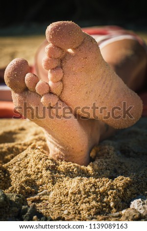 Close up of woman feet with sand at sunny beach. Holiday concept