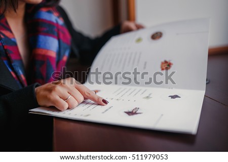 close up of woman finger with menu choosing dishes at restaurant