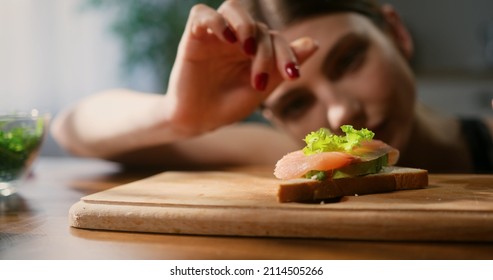 Close up of woman gently placing lettuce leaf onto salmon avocado toast. Healthy eating concept. - Powered by Shutterstock