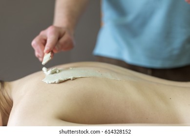 Close up woman getting clay mask on her back
