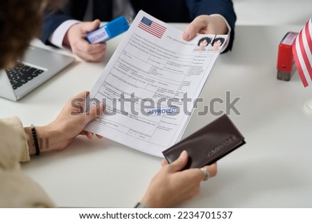 Close up of woman getting US visa in immigration office and holding approved forms