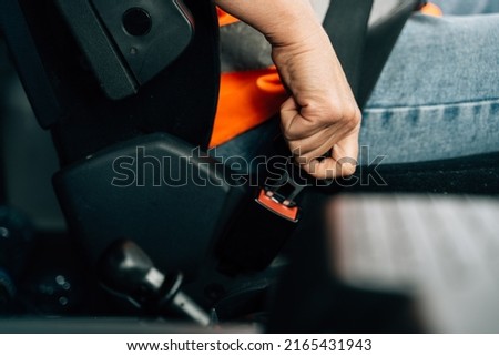 Close up of woman hand buckle the car safety belt. Truck driver occupation 
