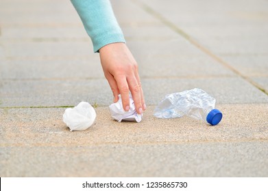 Close up of woman hand collecting garbage on the floor in the street with copy space