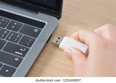 Close up of a woman hand connecting a pendrive in a laptop on a desktop