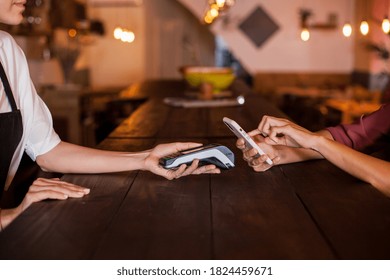 Close Up Of Woman Hand Dialing The Secret Code To Do A Contactless Payment By Phone Using NFC Technology. Paying With Just A Tap In A Coffee Shop During Daytime. Concept Technology Contactless.