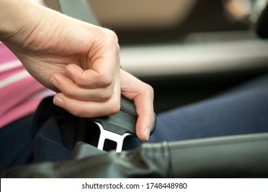 Close up of woman hand fastening seat belt while sitting inside a car for safety before driving on the road. Female driver driving secure and taking safe jorney.