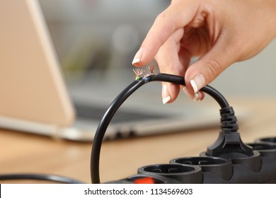 Close up of a woman hand holding a dangerous damaged electrical cord
