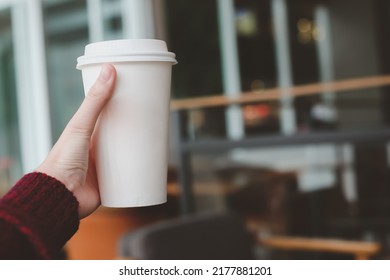 Close up of woman hand holding paper cup of hot coffee in cafe. - Powered by Shutterstock