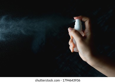 Close Up Woman Hand Holding Small Spray Bottle And Spraying On Dark Background