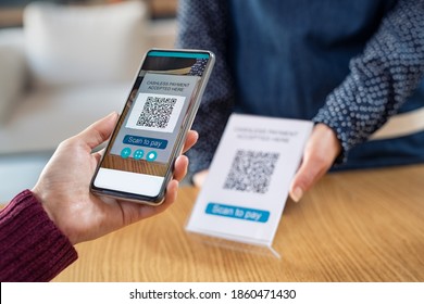 Close up of woman hand holding smartphone and scanning qr code for digital payment. Customer paying money online using mobile phone after shopping. Girl using cellphone scanner to scan qr code.